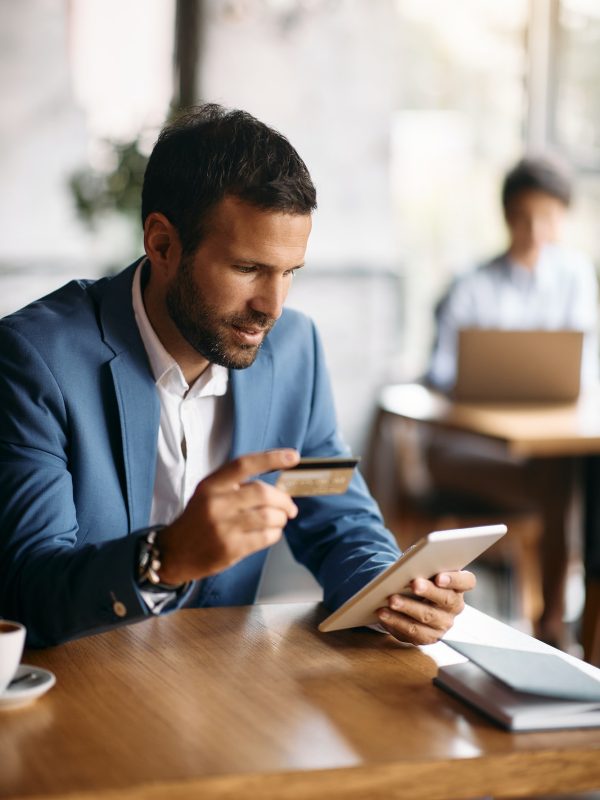 young-businessman-using-credit-card-and-digital-tablet-for-online-banking-in-a-cafe-.jpg